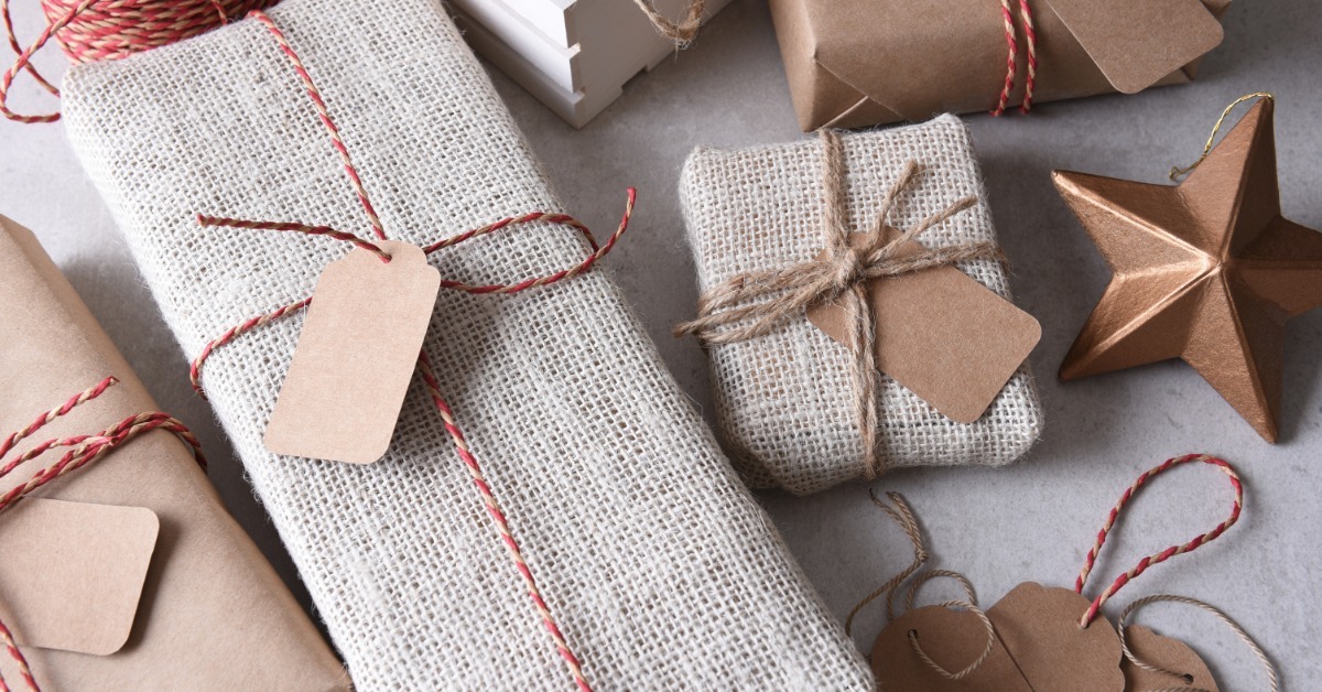 a group of fabric and paper wrapped presents with twine, blank tags, and a bronze star on a gray surface.